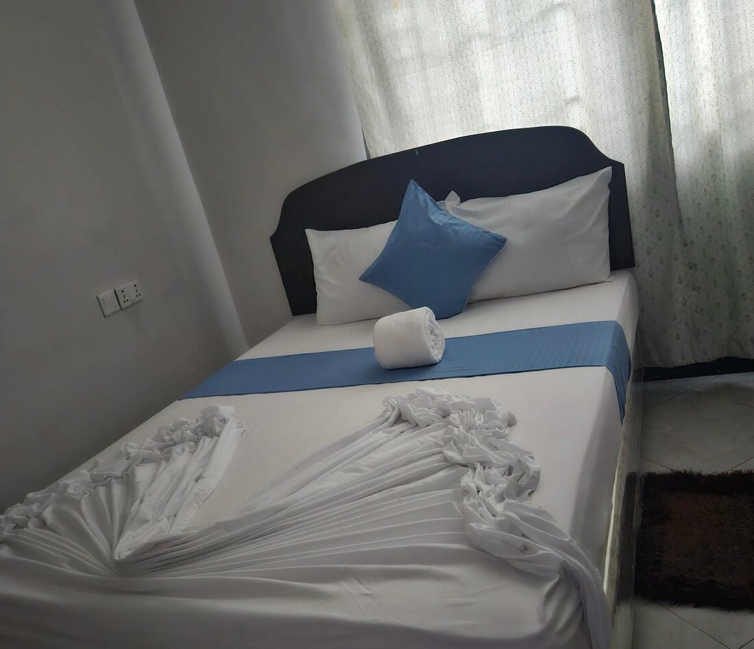 En-suite room at Rweru Hotel with a double bed and fresh white linens